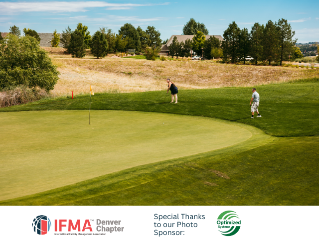 Two golfers on a green at a golf course; flag in the hole, sunny day.
