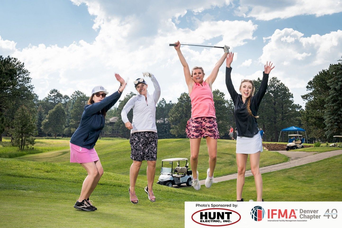 Four women celebrating on a golf course. 