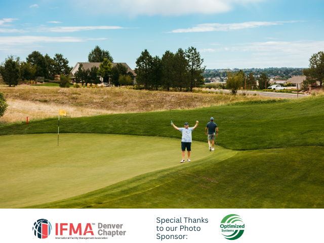 Golfers celebrating on a green. One raises arms, the other approaches. Bright green grass, blue sky.