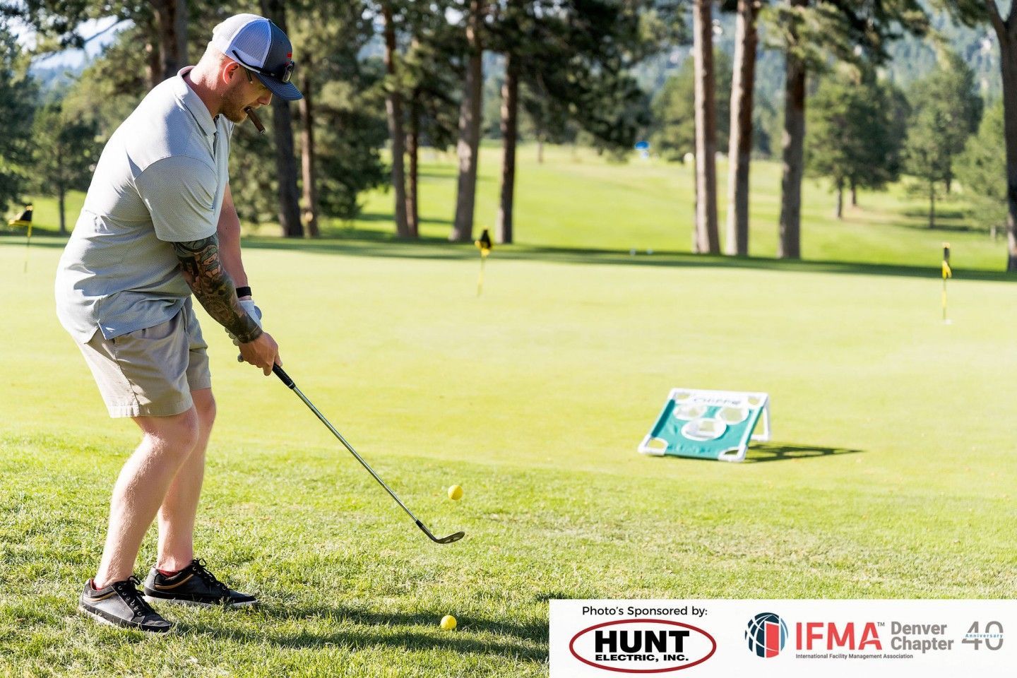 Man golfing on a green course, wearing a hat, shirt and shorts. Several golf balls are visible.