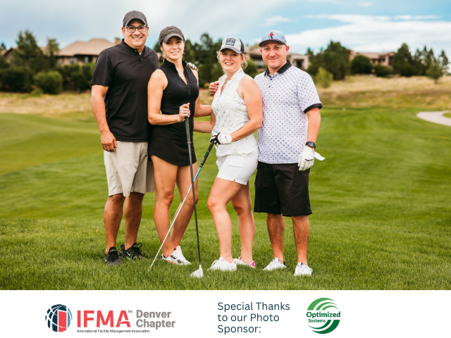 Four people on a golf course posing for a photo, holding golf clubs.