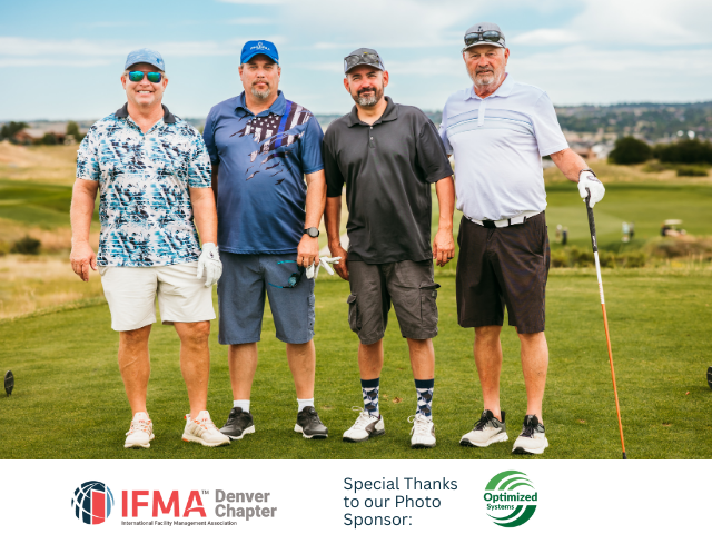 Four men standing on a golf course, smiling at camera. Wearing golf attire. Green grass and blue sky background.