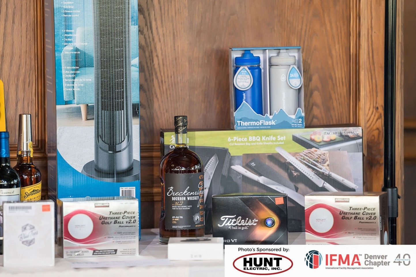 Prizes on display for an event, including a fan, wine, golf balls, water bottles, and a knife set.