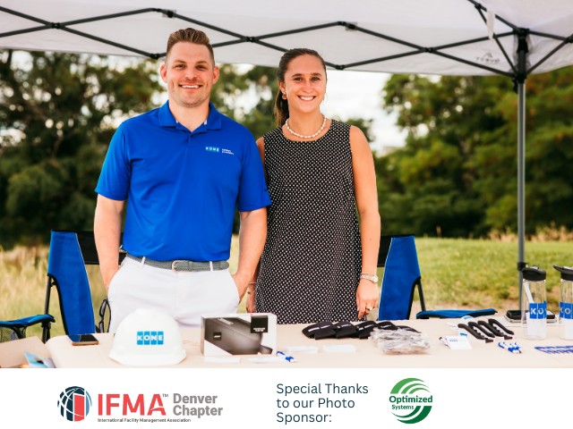 Two people smiling at a table under a tent. Man in blue shirt, woman in patterned dress. IFMA logo.