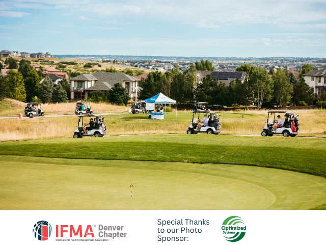 Golfers in golf carts on a course with houses in the background on a sunny day.