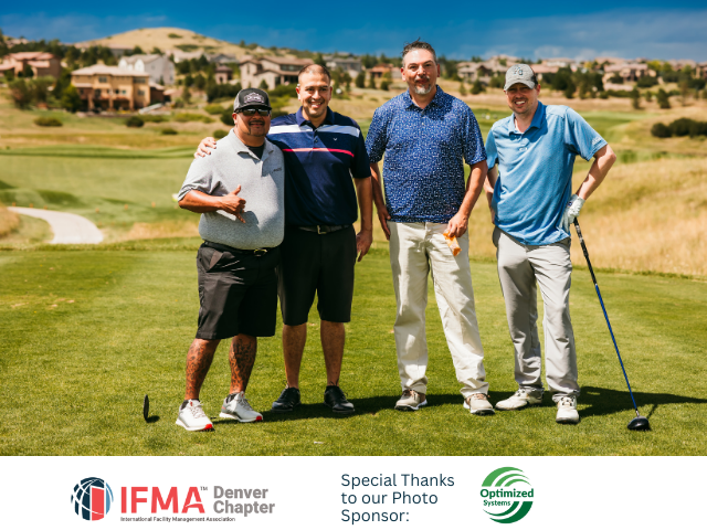 Four men pose on a golf course.