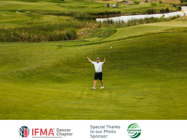 Man on golf course celebrates with arms raised. Green field, water, and golf flags are in background.