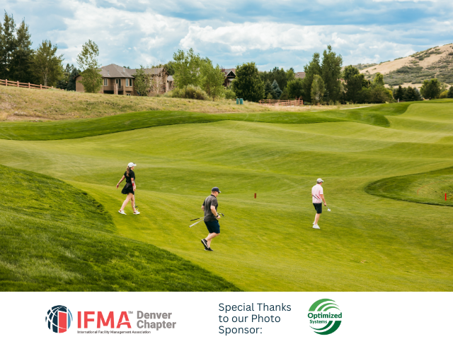 Three people on a golf course. Green grass, hilly landscape with a house.