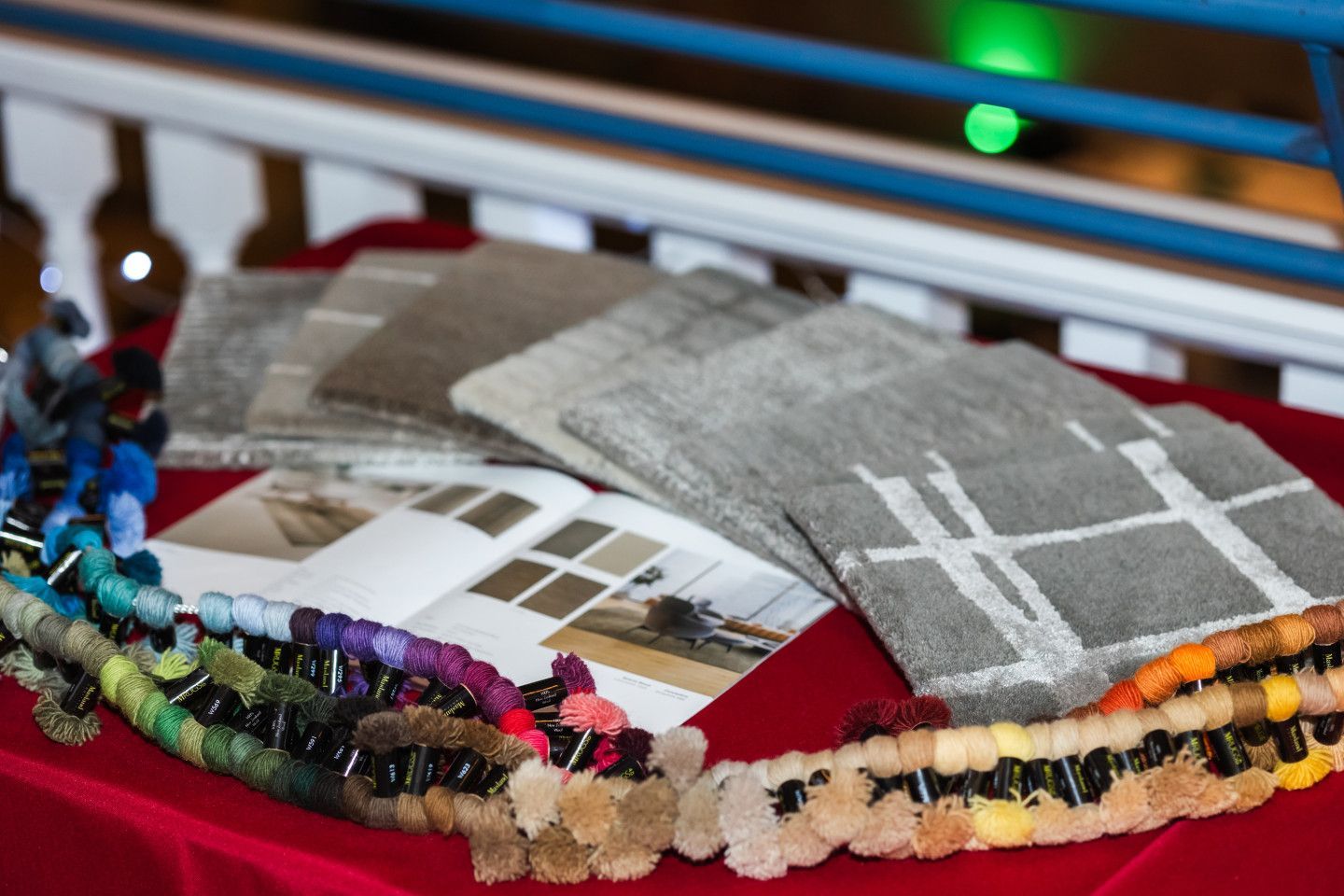 Samples of carpets and yarn colors on a red tablecloth.