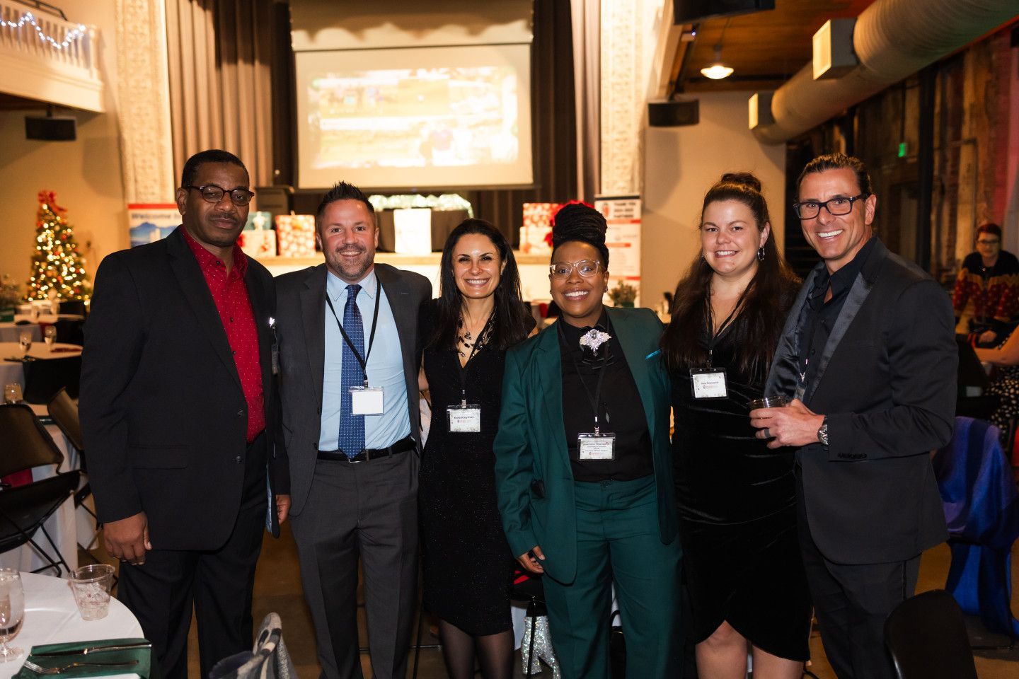 Group of six people posing for a photo at an event, wearing formal attire.