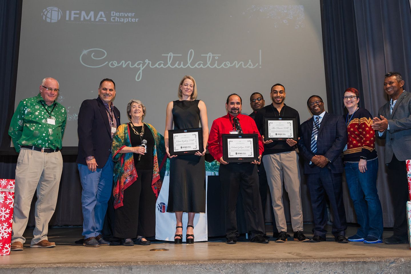 Group of people on stage holding certificates, with