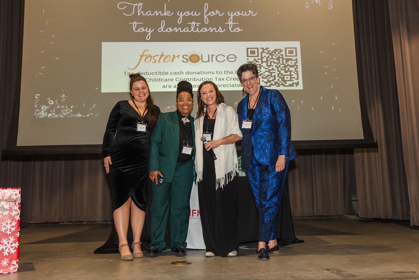 Four people stand onstage with a