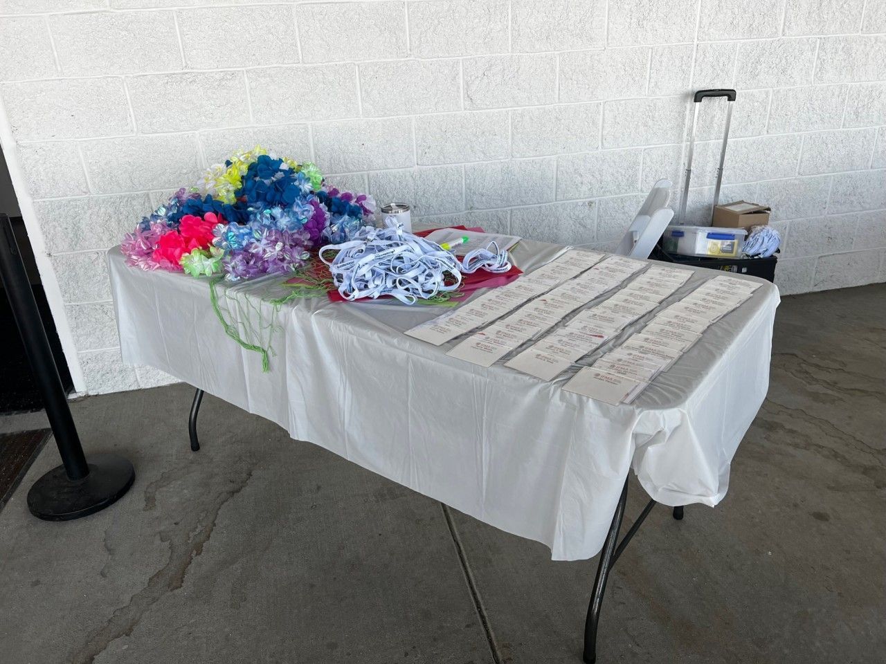 Table with leis, ribbons, and name tags set up outside.