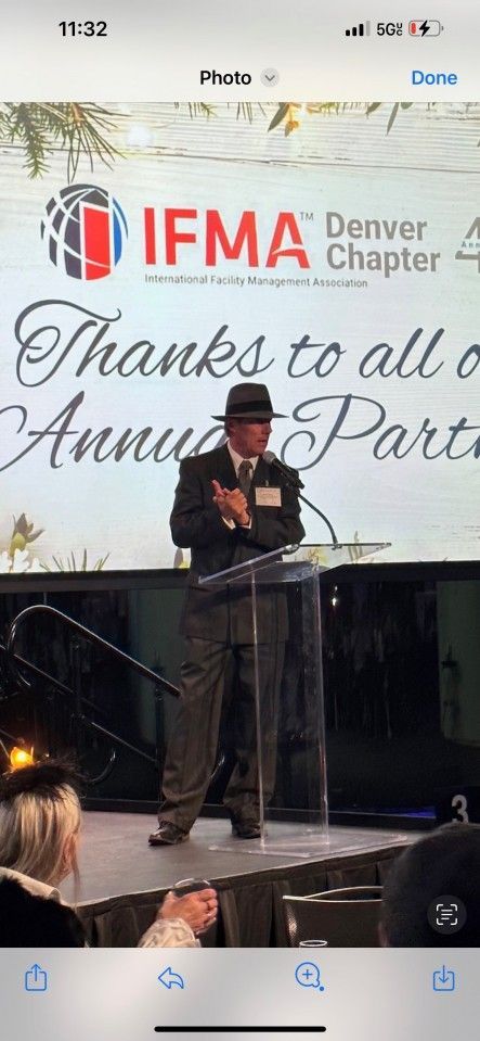 Man in a suit speaks at a podium; IFMA Denver Chapter logo in the background.
