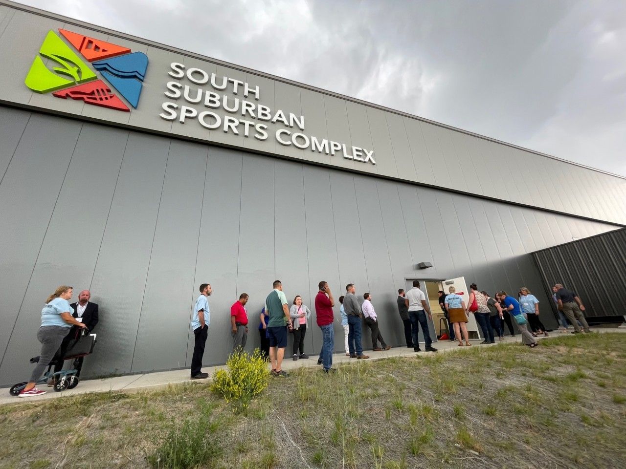 South Suburban Sports Complex exterior; people line up outside a door under a gray cloudy sky.
