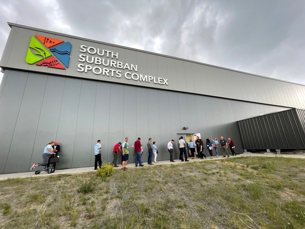 People line up outside the South Suburban Sports Complex on a cloudy day.