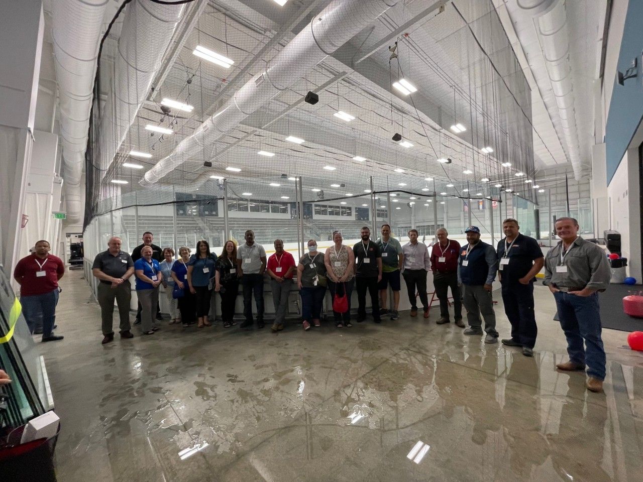 Group of people standing in an indoor ice rink, posing for a photo.