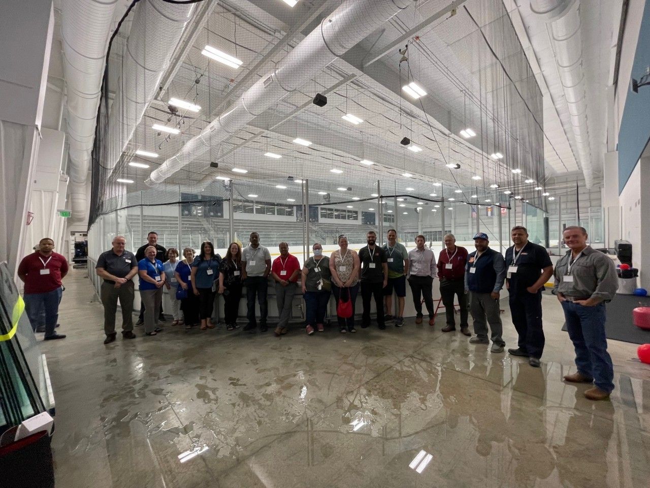 Group of people standing on an indoor ice rink, likely a tour or event.