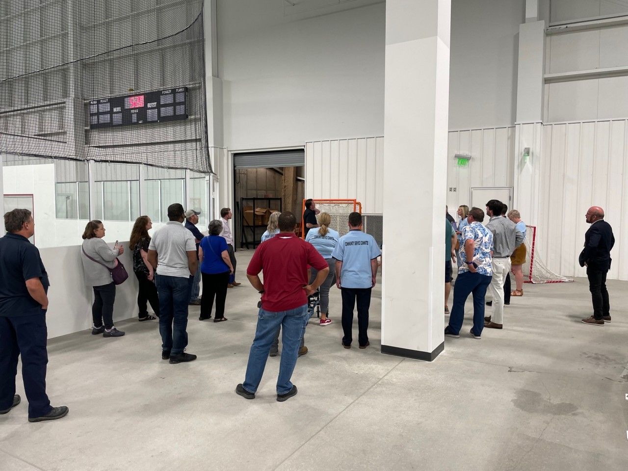 Group of people in an indoor sports facility, looking at hockey goals and other equipment.