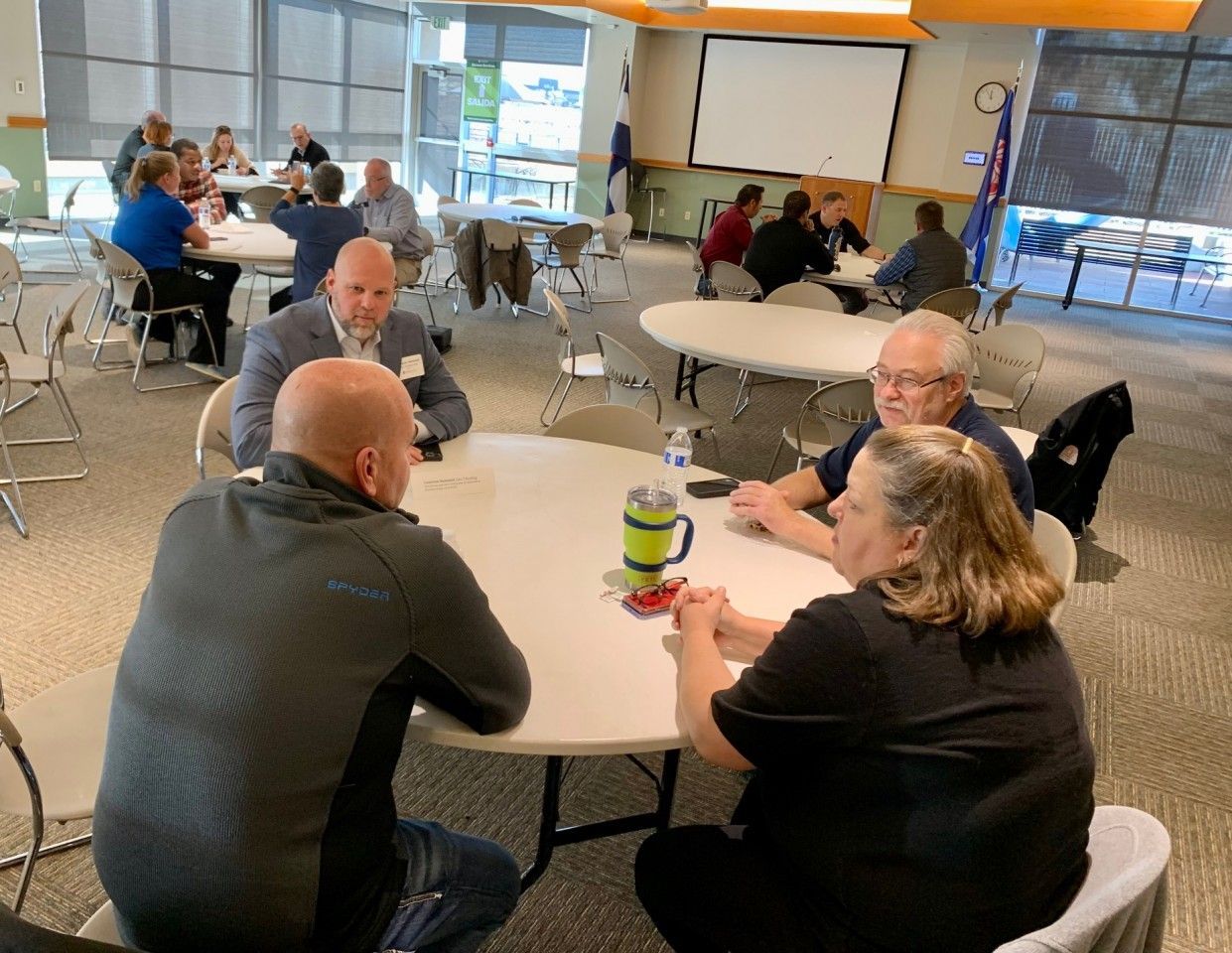 People sitting at round tables in a large room, likely a meeting or event.