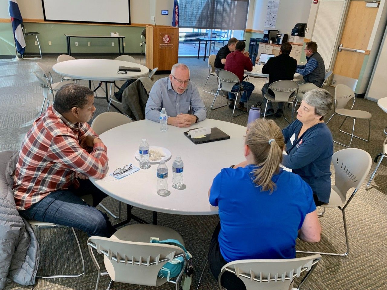 People in small groups at round tables, having a meeting in a conference room.