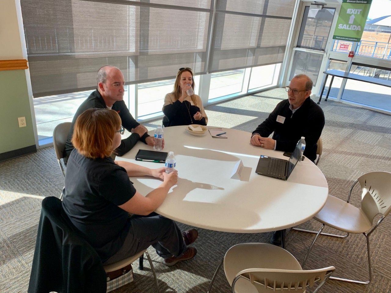 Four people seated around a white table indoors