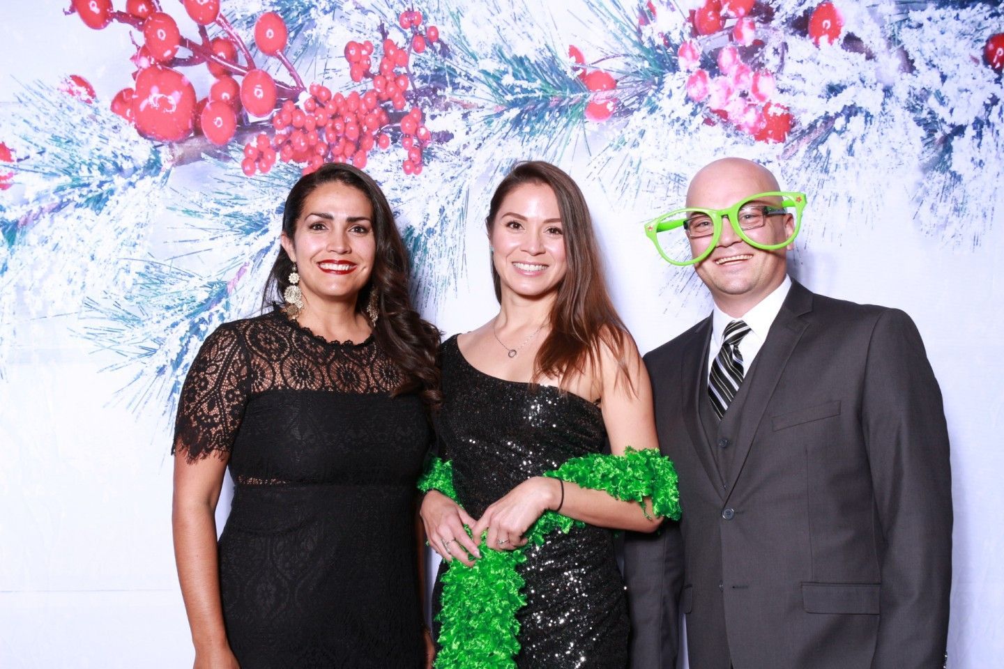 Three people pose in front of a festive backdrop.