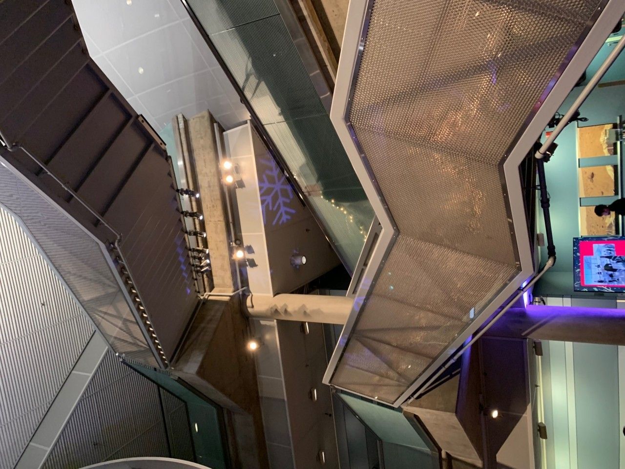 An interior view of a modern building with angular metal walkways and glass walls.