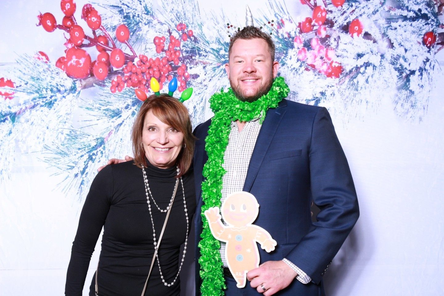 Woman and man posing in front of a holiday backdrop.