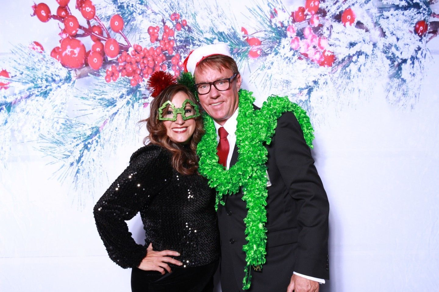 Two people smiling, posing in front of a holiday backdrop.