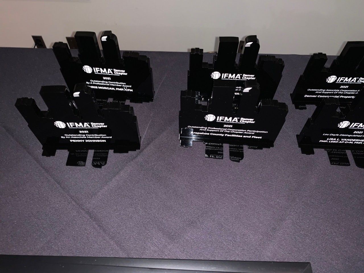 Six black, hand-shaped awards with logos and text sit on a dark surface.