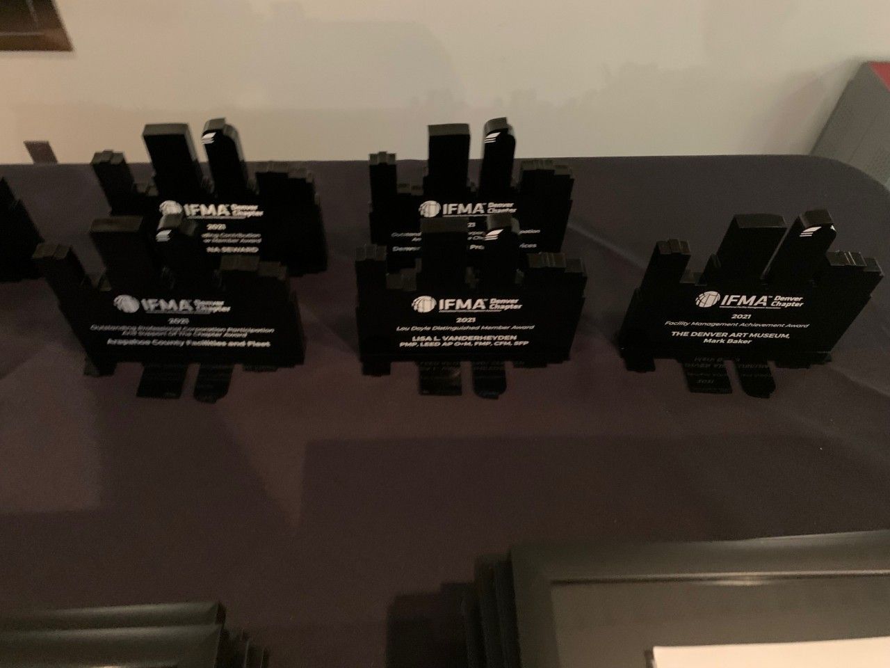 Six black awards with text on a dark table; the text is difficult to read.