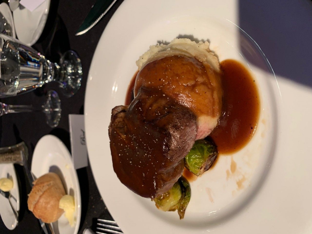 Plate with roasted meat, mashed potatoes, sauce, and Brussels sprouts.