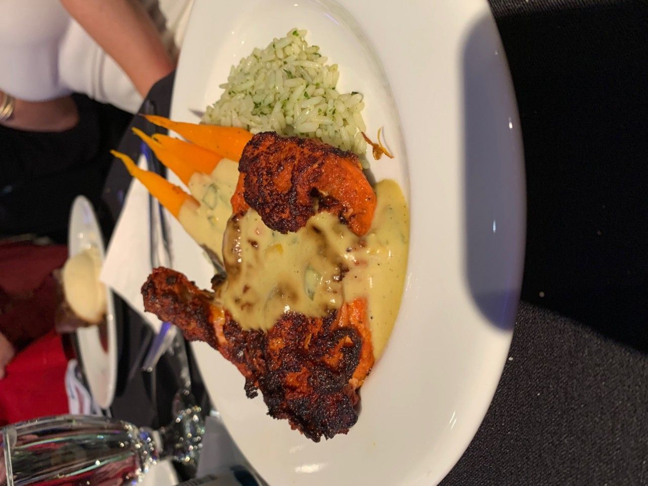 Plate of food: roasted chicken with sauce, carrots, and green rice.