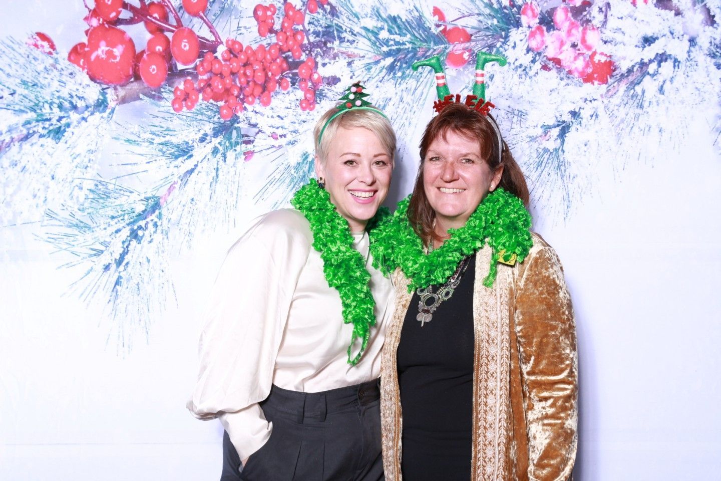 Two people in festive attire posing in front of a holiday backdrop.