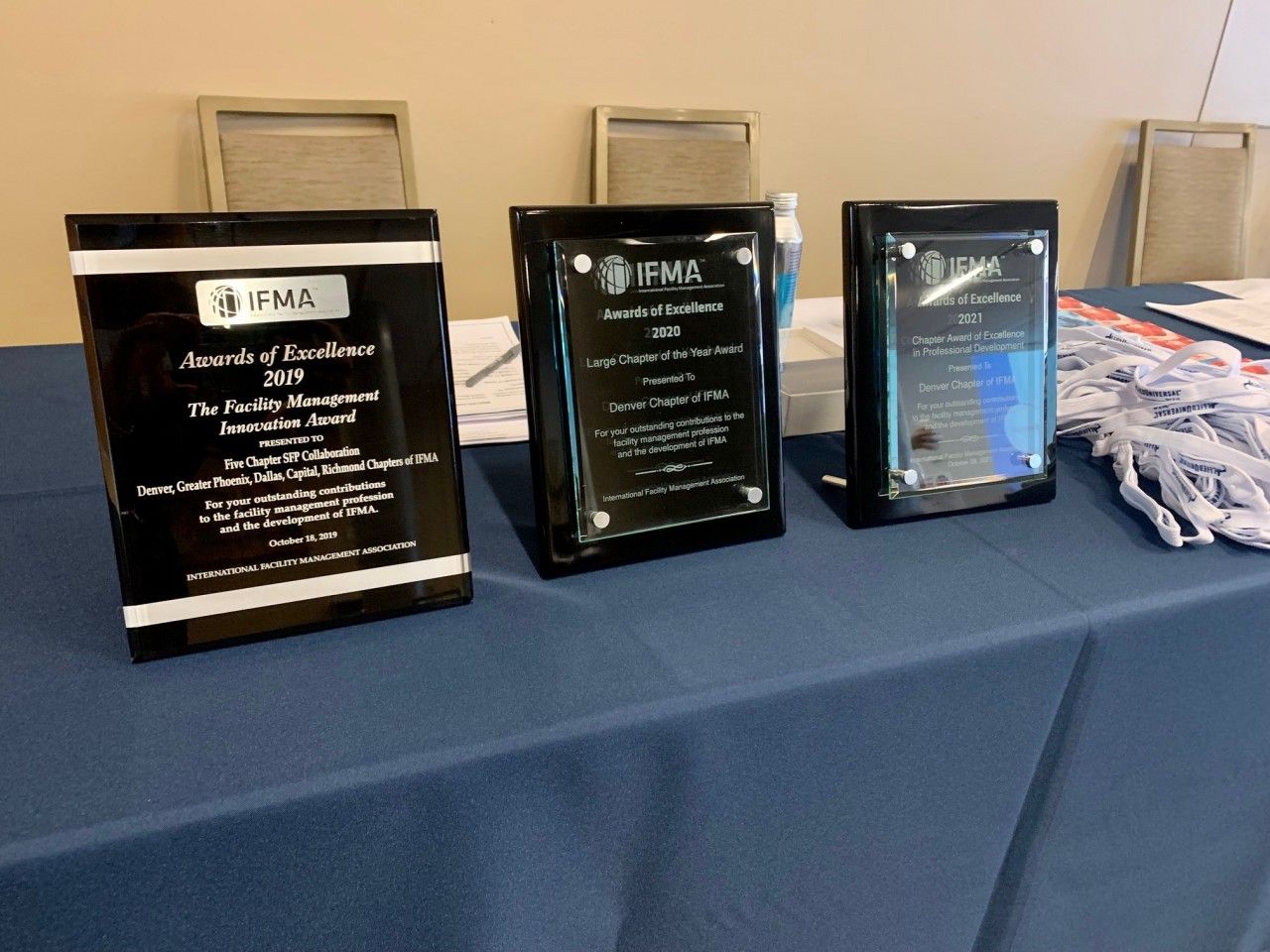 Three black plaques on a blue table, showcasing awards from IFMA, the International Facility Management Association.