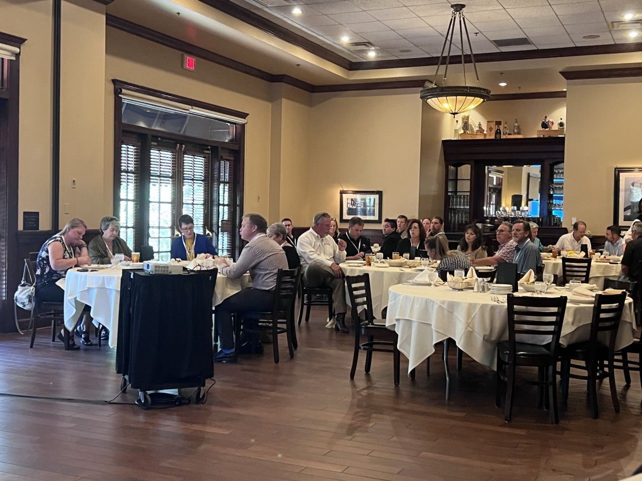 Group seated at round tables in a restaurant, presumably a meeting or event.