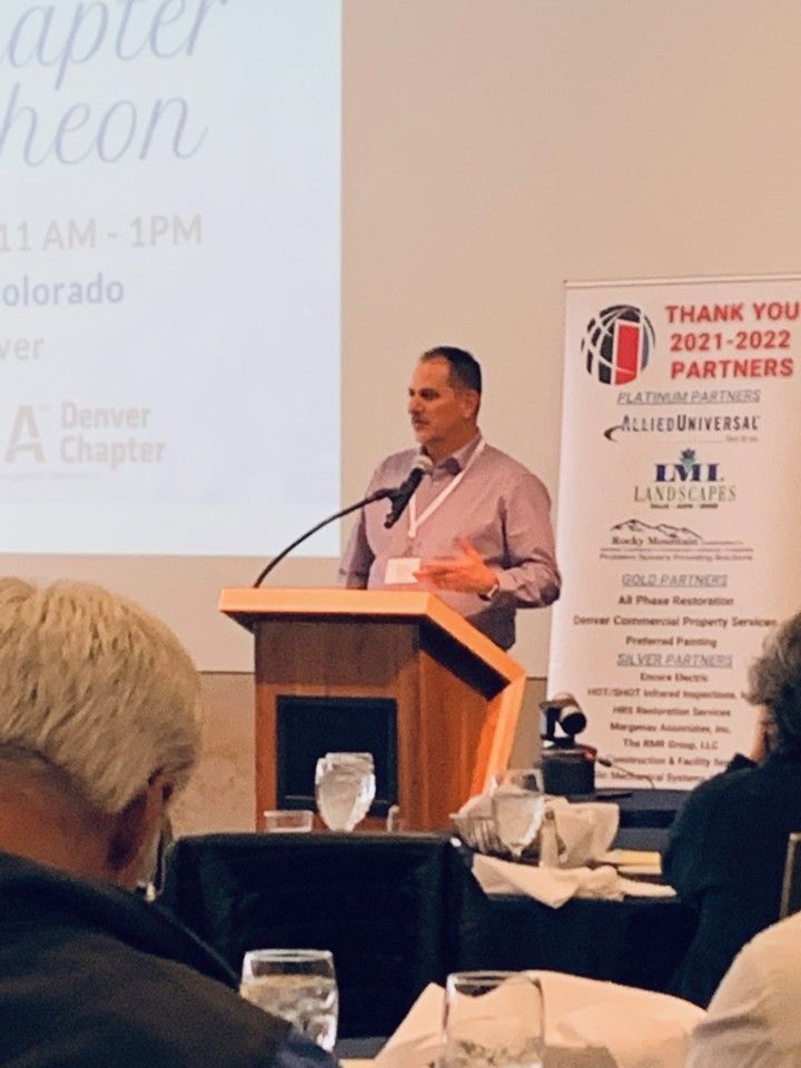 Man speaking at a podium during a conference. Banner reads 
