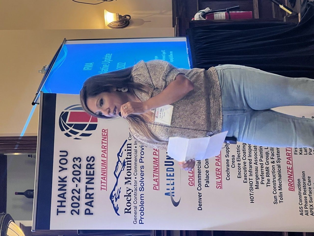 Woman speaking at a podium with a banner that reads 