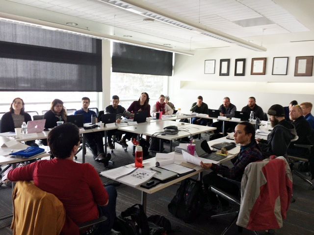 A group of people sitting around a large table in an office, discussing documents.