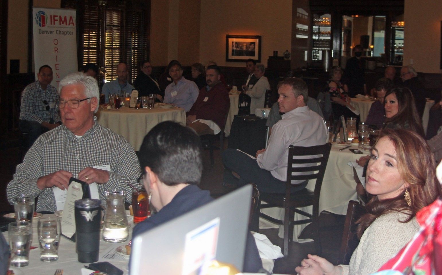 People seated at tables in a restaurant for a meeting; some are looking forward.