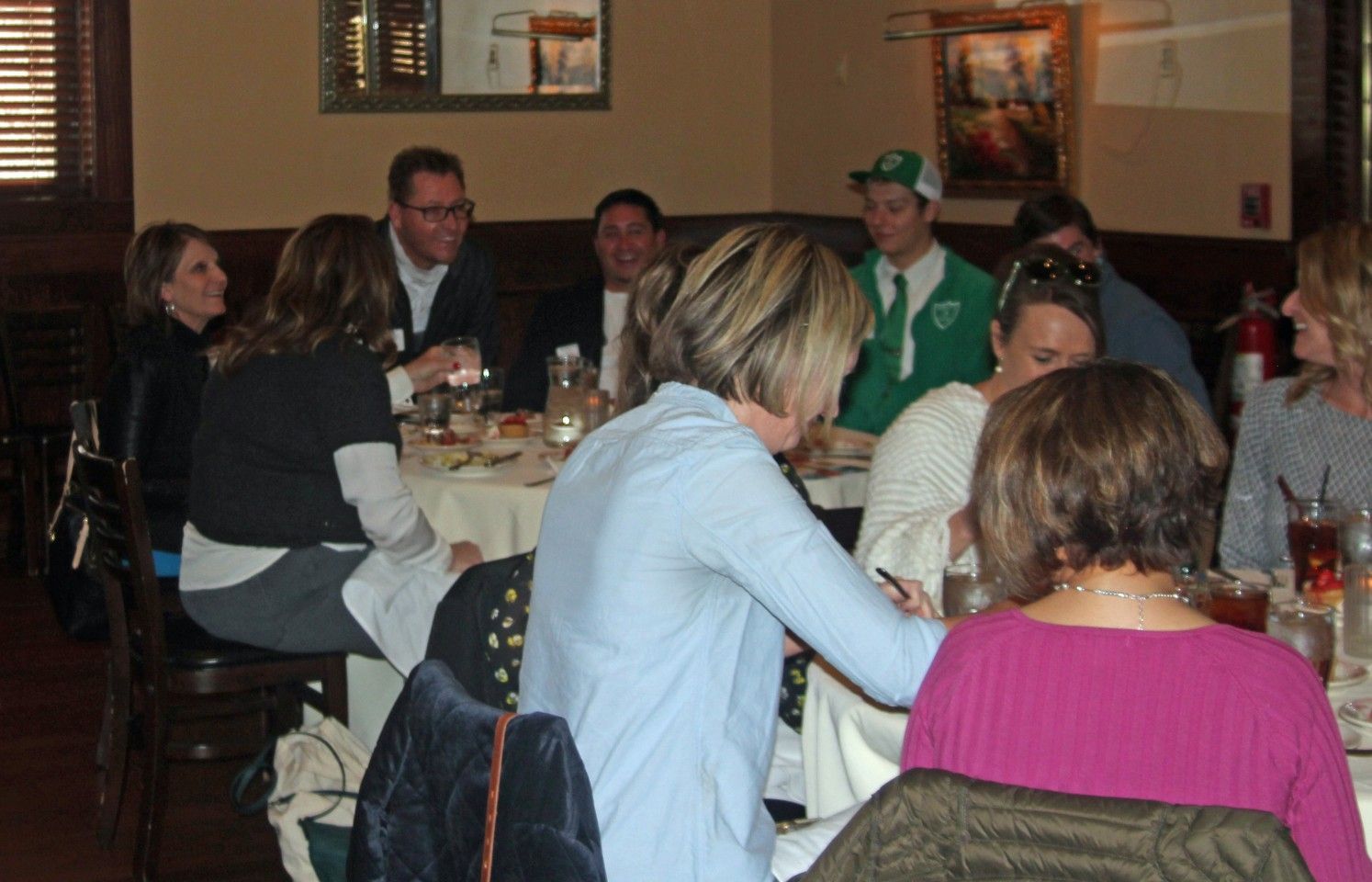 People seated around a table at a restaurant. Some are talking, others are eating.