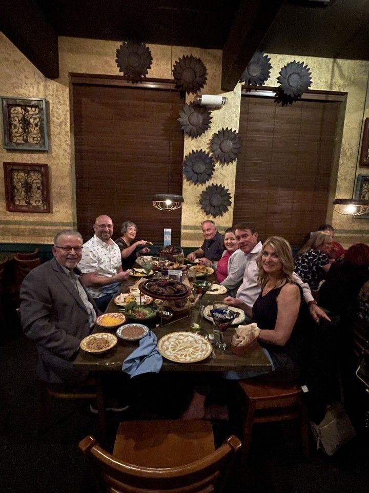 Group of people dining at a restaurant, seated around a table with food.