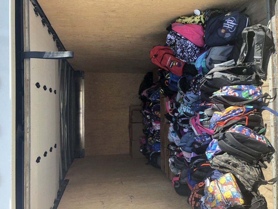Inside of a cargo trailer filled with colorful backpacks, presumably for donation.