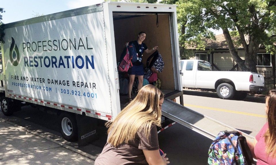 People unloading items from a truck marked 
