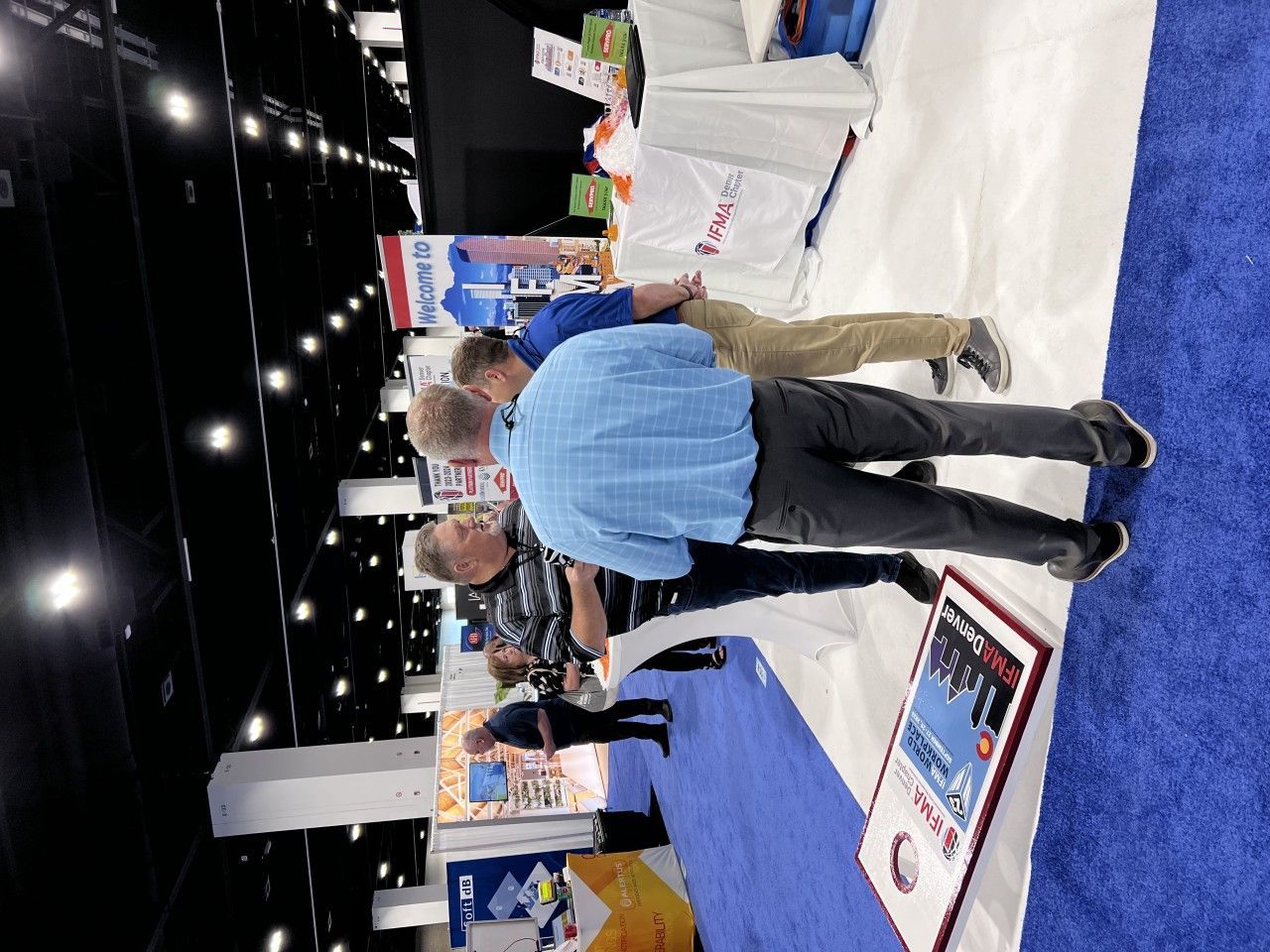 People at a trade show booth, viewing items.