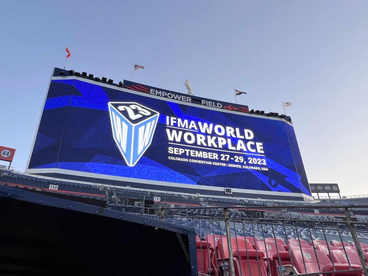 Large stadium screen promoting IFMA World Workplace conference, September 27-29, 2023, at Empower Field.