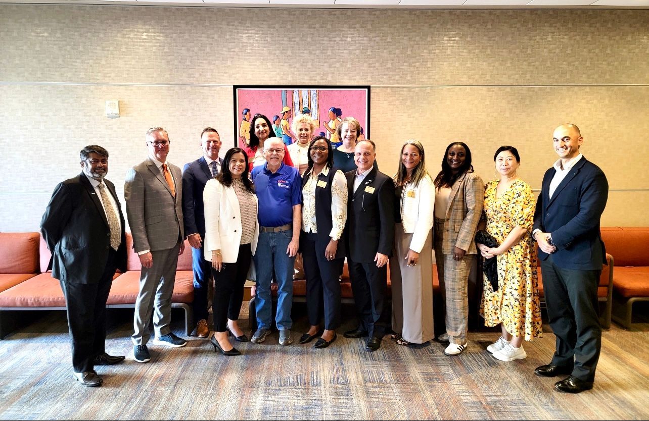 Group of people posing in front of a colorful artwork. Indoor setting with a couch.