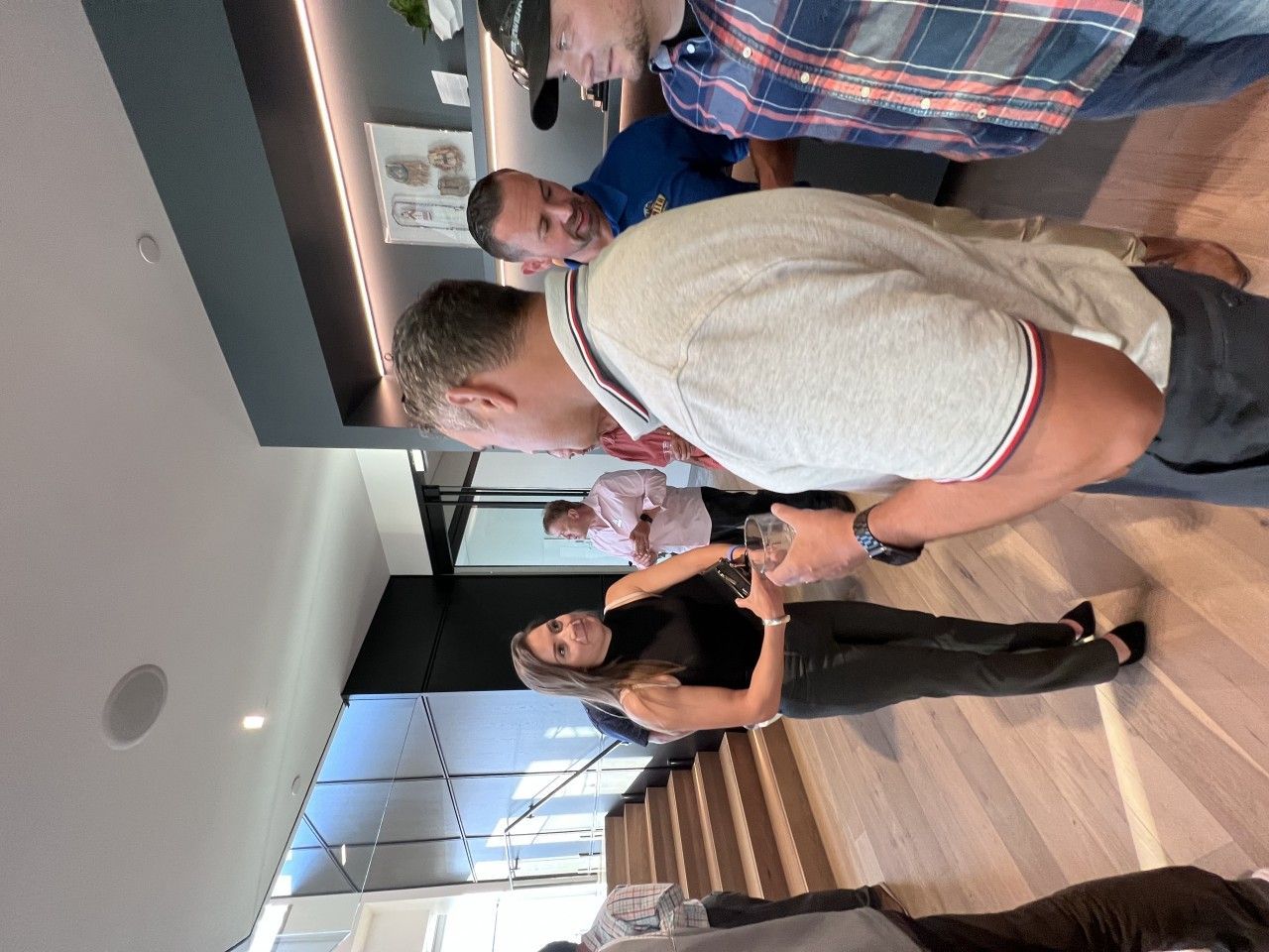 People in a modern office space, some looking down, possibly at something held in their hands.