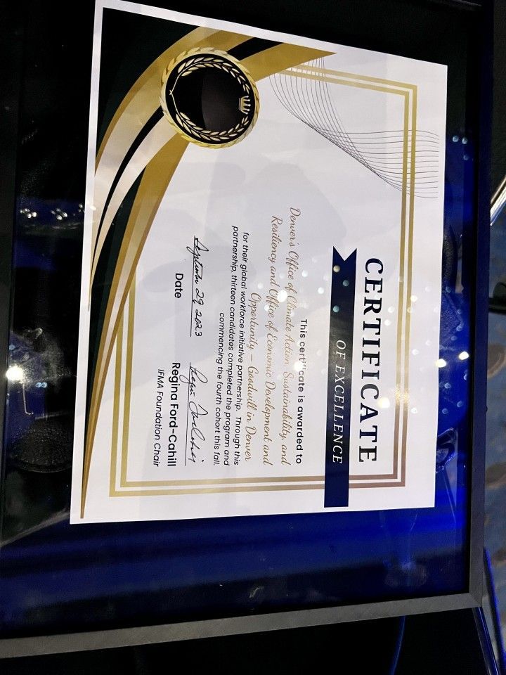 Certificate of Excellence in a shadow box, gold and black design with blue backdrop.
